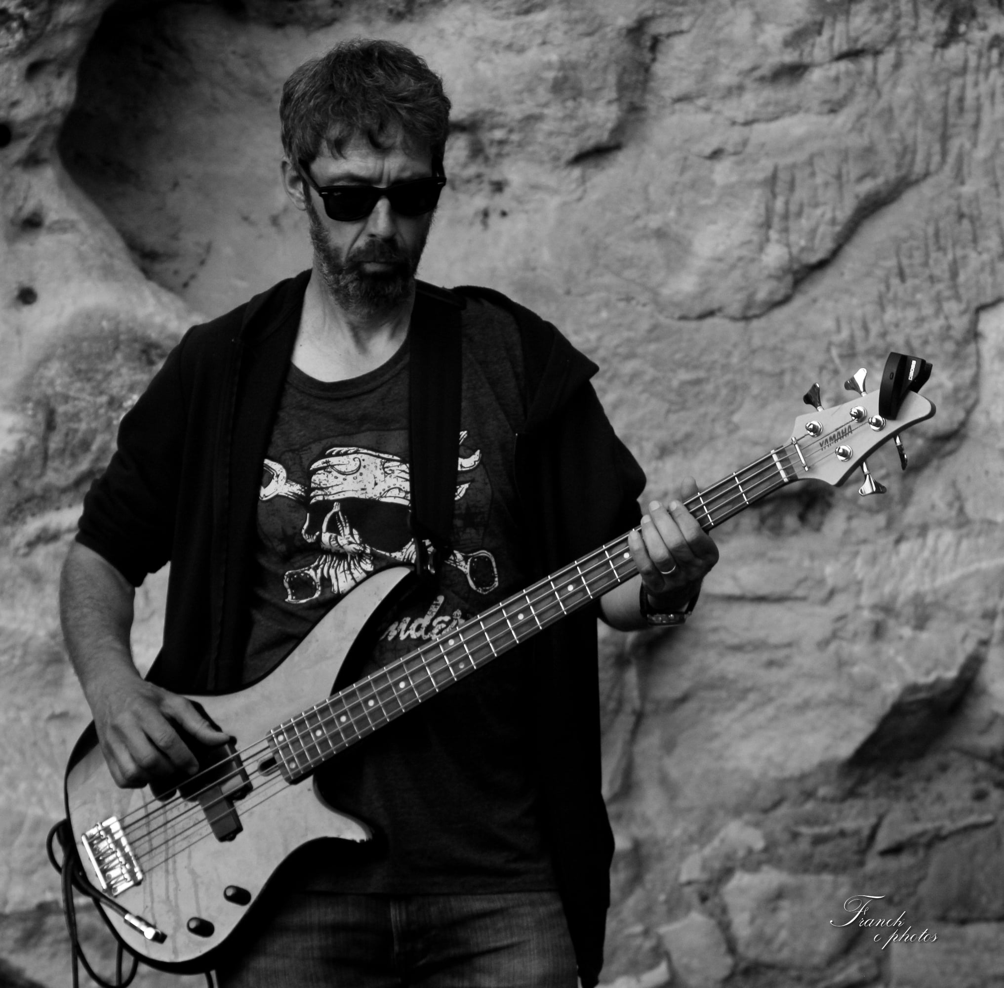 une photo en noir et blanc de BassMan avec ses lunettes noires et sa basse